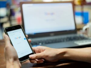 An internet user searching a query guided by Google Search Statistics on a mobile device with a computer background on google homepage.